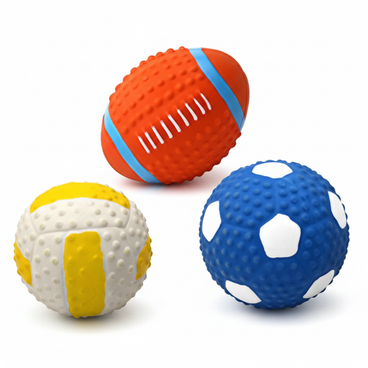 Three sports-style squeaky rubber dog toy balls: rugby, volleyball, and soccer ball
