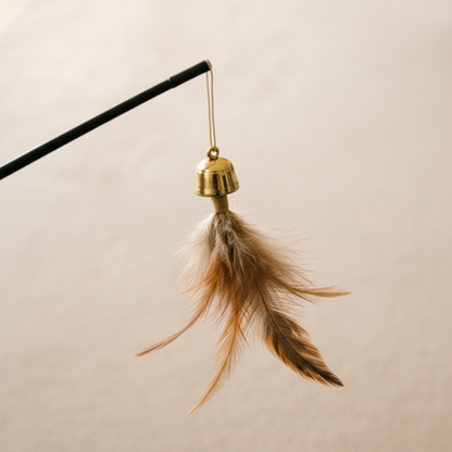 Close-up of gold bell charm and feather tassel attachment on cat teaser wand